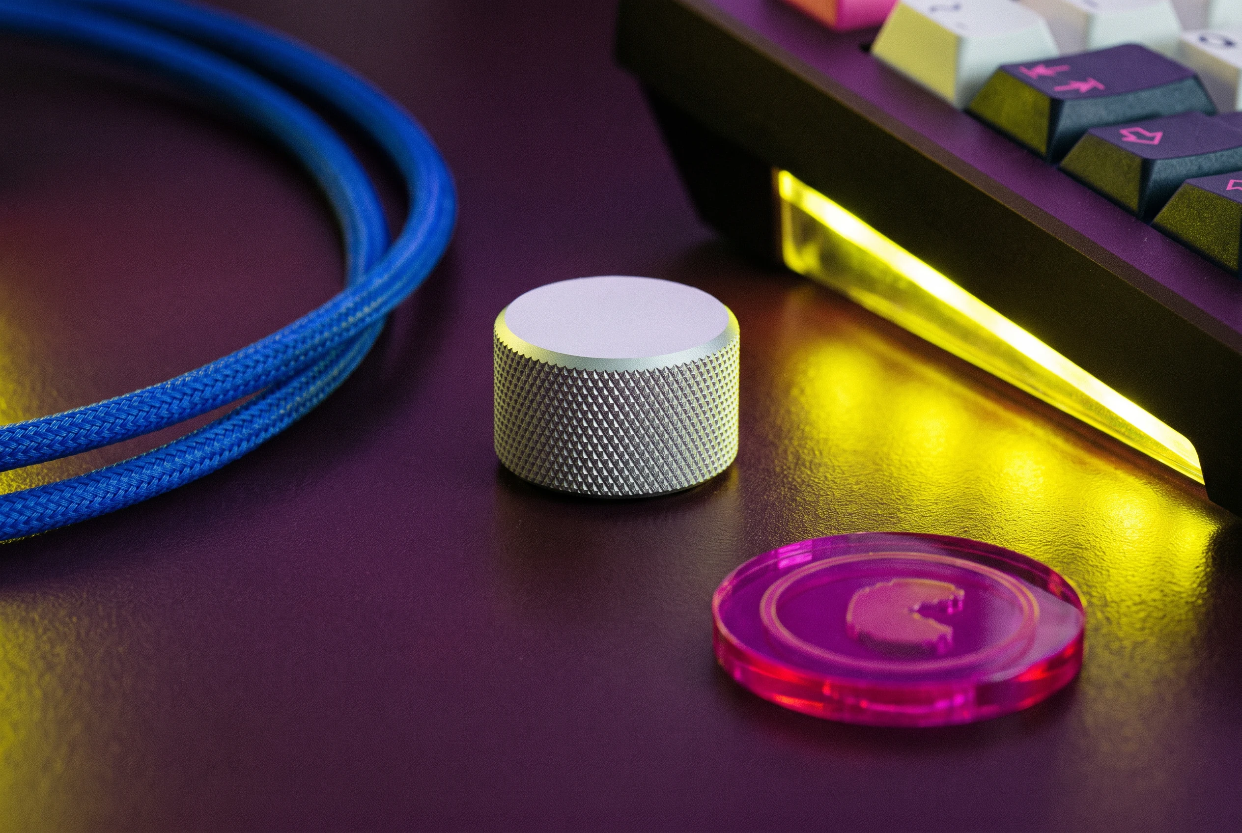 Close view of a silver control knob beside a keyboard and coloured light